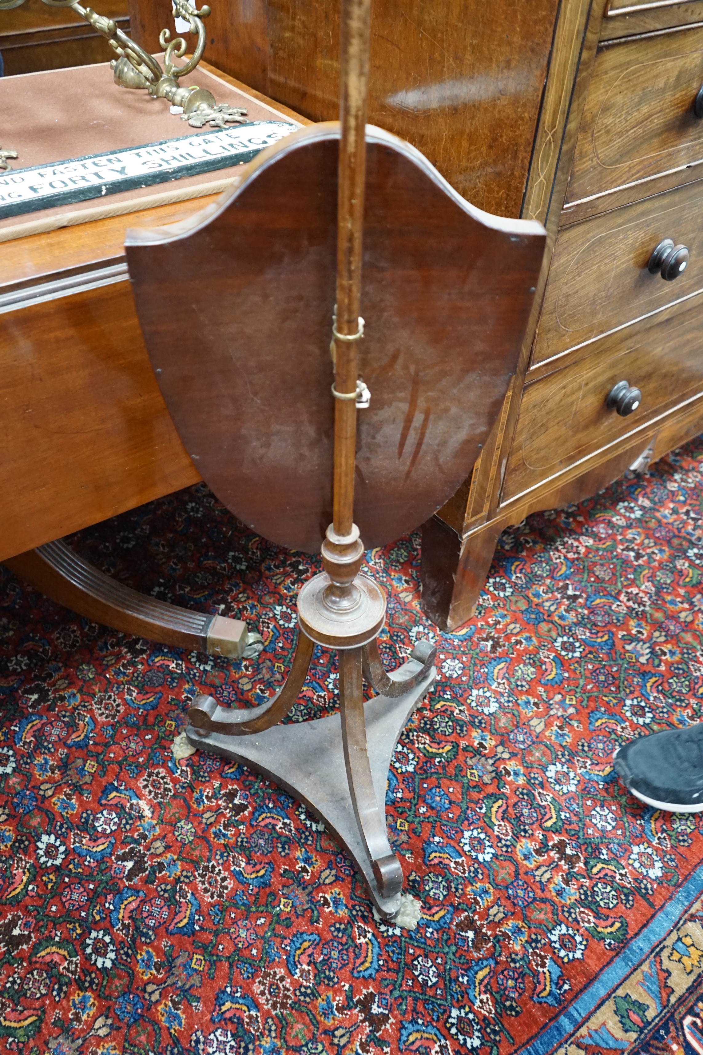 Two early 19th century shield shaped mahogany pole screens with silk embroidered banners, larger height 150cm